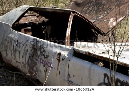 An old abandoned car body that is covered in graffiti.