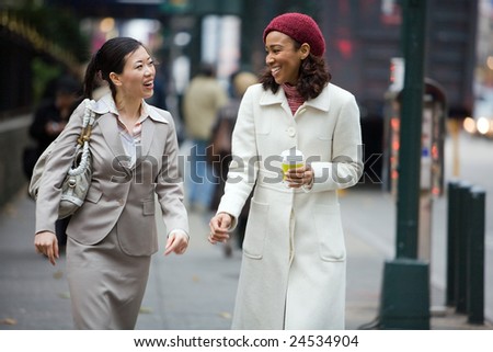 Two business women having a conversation while walking in the big city.