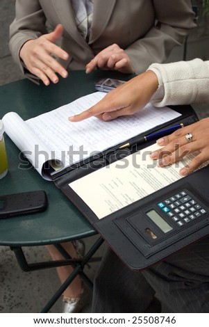 Two women having a discussion and sharing information during a business meeting.  Shallow depth of field.