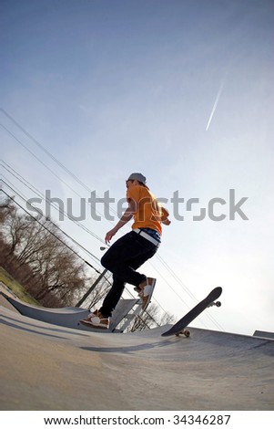 Portrait of a young skateboarder falling off of his board on a ramp at the skate park.