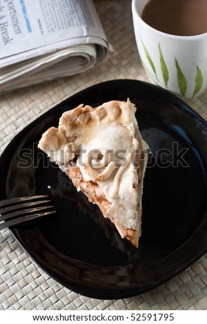 A slice of fresh homemade deep dish apple pie on a plate with a hot coffee and the newspaper.  The perfect dessert or breakfast.  Shallow depth of field.