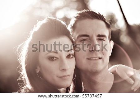 A good looking young couple posing together.  Back lit lighting with strong lens flare and sepia tone.