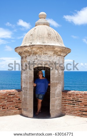 A tourist poses in an old fort watch tower located in Old San Juan Puerto Rico at the historic San Cristobal fortification.