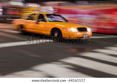 Abstract blur of a night time urban street scene with a yellow taxi cab speeding by.  Slow shutter speed panning technique used for motion blur.