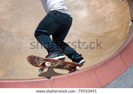 Action shot of a young skateboarder skating sideways against the wall of the bowl at a skate park.