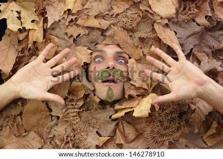 funny man under a bed of falling leaves, an autumn concept