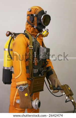 The mannequin is dressed in a orange diving suit with a cargo, hoses and oxygen cylinders