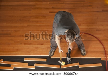 Top view of a man installing planks of hardwood floor