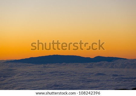 Sunset above the clouds. The view of the island of Maui, from the Mauna Kea volcano on the Big Island, Hawaii.