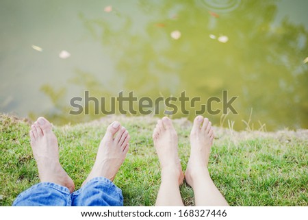 legs of couple on the grass near the lake