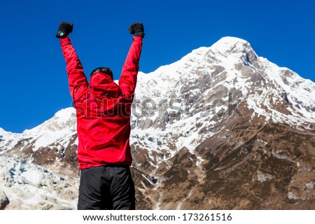 Winner / Success concept. Hiker cheering elated and blissful with arms raised in the sky after hiking to mountain top summit above the clouds