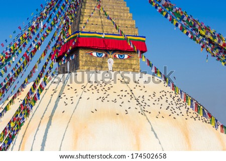 bodhnath stupa in kathmandu with buddha eyes and prayer flags with clear blue sky
