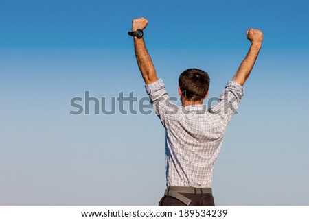 Handsome joyful businessman businessman raising his arms upwards show the victory to the world