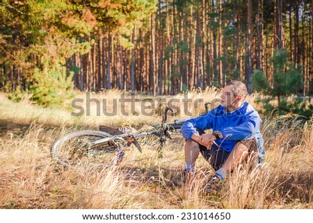 Cyclist with bike have a rest in autumn forest