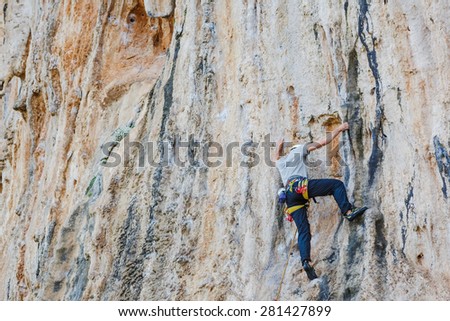 Young man climbing on a wall with quick-draws