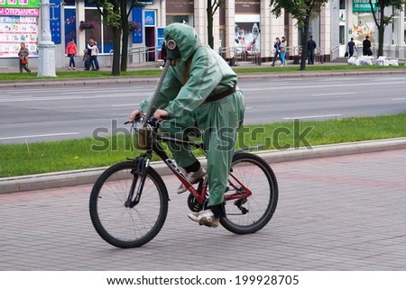 MINSK, BELARUS - JUNE 16, 2014: Man in a gas mask and protective costume riding a Bicycle. The photo illustrates the danger of environmental pollution.