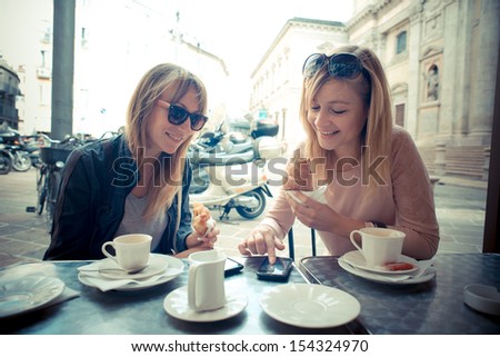 two beautiful blonde women talking at the bar in the city