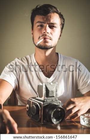young stylish hipster man with old camera on the table at home