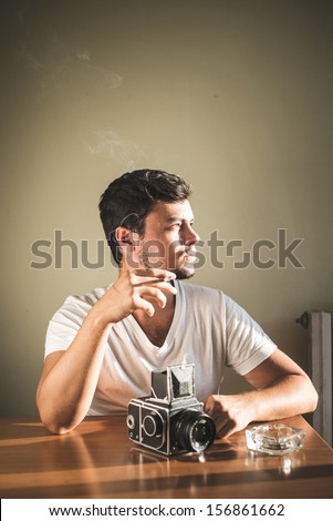young stylish hipster man with old camera on the table at home