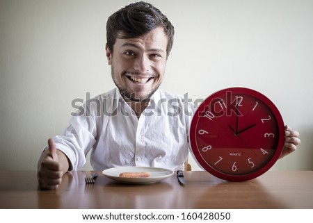 funny puppets man with white shirt holding red clock behind a table