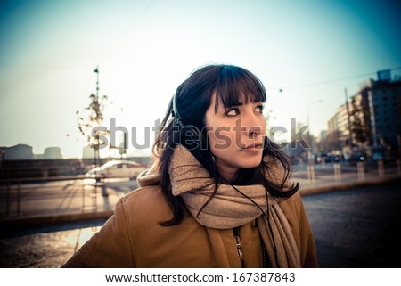 beautiful young woman listening to music headphones  in the city winter