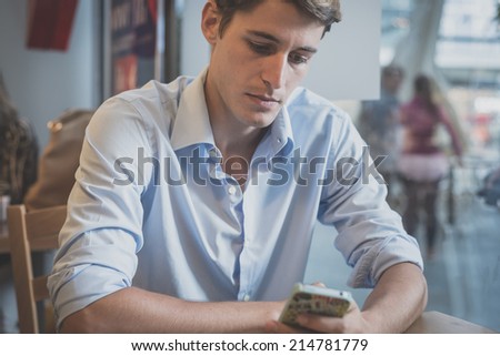 young model handsome blonde man using smartphone at the bar