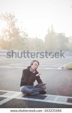 young crazy funny asian man in town outdoor lifestyle listening music with headphones and tablet