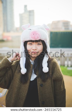 young beautiful asian hipster woman in the city - wearing funny piggy winter cap