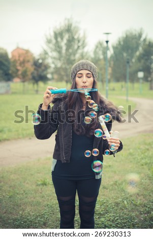 young beautiful brunette woman blowing bubbles soap in the city