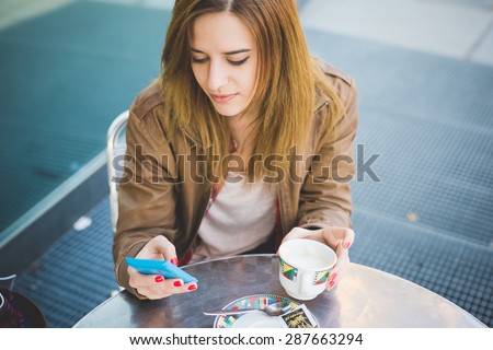 young beautiful blonde hipster woman at the cafe bar using smartphone