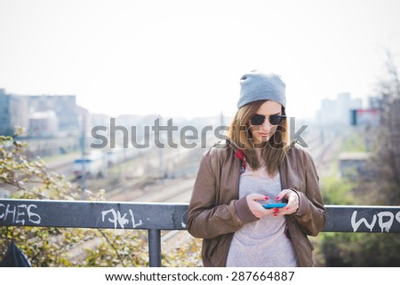 young beautiful blonde hipster woman in the city using smartphone connected online