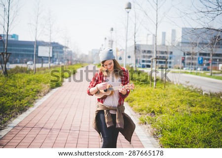 young beautiful blonde hipster woman in the city with ukulele