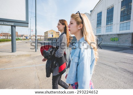 Two women friend blonde and brunette walking through the city having fun - emancipation, friendship concept