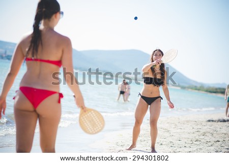 two beautiful young woman playing with racket at the beach on the foreshore - sport, relax, fun concept