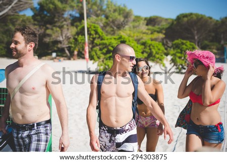 group of young multiethnic friend group of young multiethnic friends women and men at the beach in summertime walking
