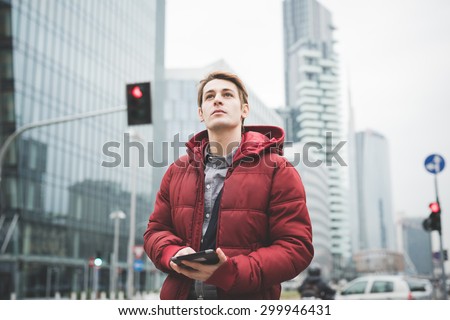 Half length of a young handsome caucasian contemporary businessman walking through the city using a tablet overlooking - technology, network, business, finance concepts