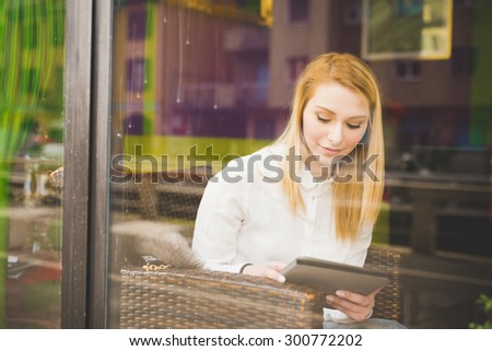 young beautiful blonde straight hair woman in the city sitting at the restaurant using tablet - relax, technology, social network concepts