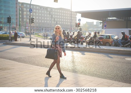 Young beautiful caucasian blonde girl listening to music walking through the city with headphones  overlooking right - relax, youth, emancipation concept