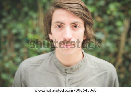 Portrait of a young beautiful caucasian man with moustache looking in camera - freshness, serene, carefree concept
