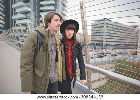 Couple of beautiful woman and man, with moustache and skate,walking through the streets of the city hugging - freshness, youth, carefreeness concept