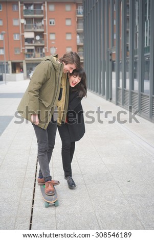 Couple of beautiful woman and man, with moustache and skate,walking through the streets of the city hugging, playing and chatting- freshness, youth, carefreeness concept