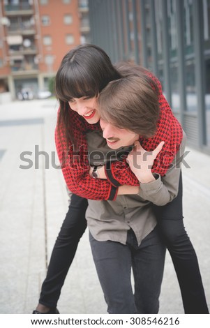 Couple of beautiful woman and man, with moustache and skate,walking through the streets of the city hugging, playing and chatting- freshness, youth, carefreeness concept