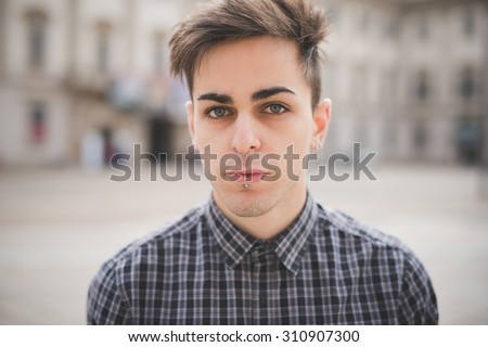 Portrait of a young handsome alternative dark model man looking in camera with central labret and nostril piercing - youth, rebellion,diversity concept
