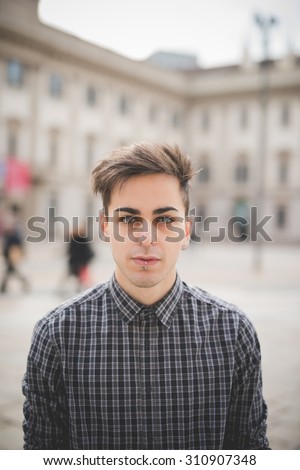 Half length of a young handsome alternative dark model man looking in camera with central labret and nostril piercing - youth, rebellion,diversity concept
