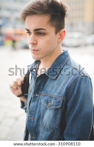 Half length of young handsome alternative dark model man posing in the street with centrale labret and nostril piercing looking right - rebellion, youth, diversity concept