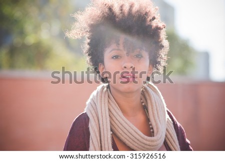 half length of a young beautiful black curly hair african woman looking in camera, pensive - pensive, serious, youth concept