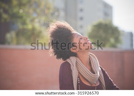 half length of a young beautiful black curly hair african woman smiling with eyes closed - serenity, carefreeness, youth concept