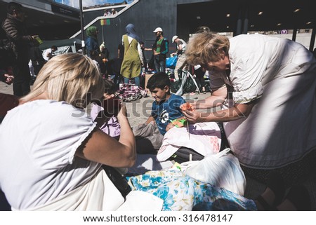 BUDAPEST - SEPTEMBER 7 : War syrian refugees at the Keleti Palyaudvar Railway Station on 1 September 2015 in Budapest, Hungary. Woman hungarian volunteer playing with children, making paper flowers