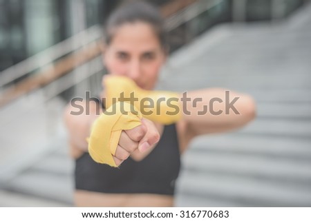 Half length of a young handsome caucasian brown hair boxer woman boxing, looking in camera, focus on fist - sportive, training, healthy, fitness concept