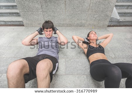 Couple of handsome caucasian sportive man and woman doing abdominal lying on the floor - sportive, healthy, training, practice, fitness concept